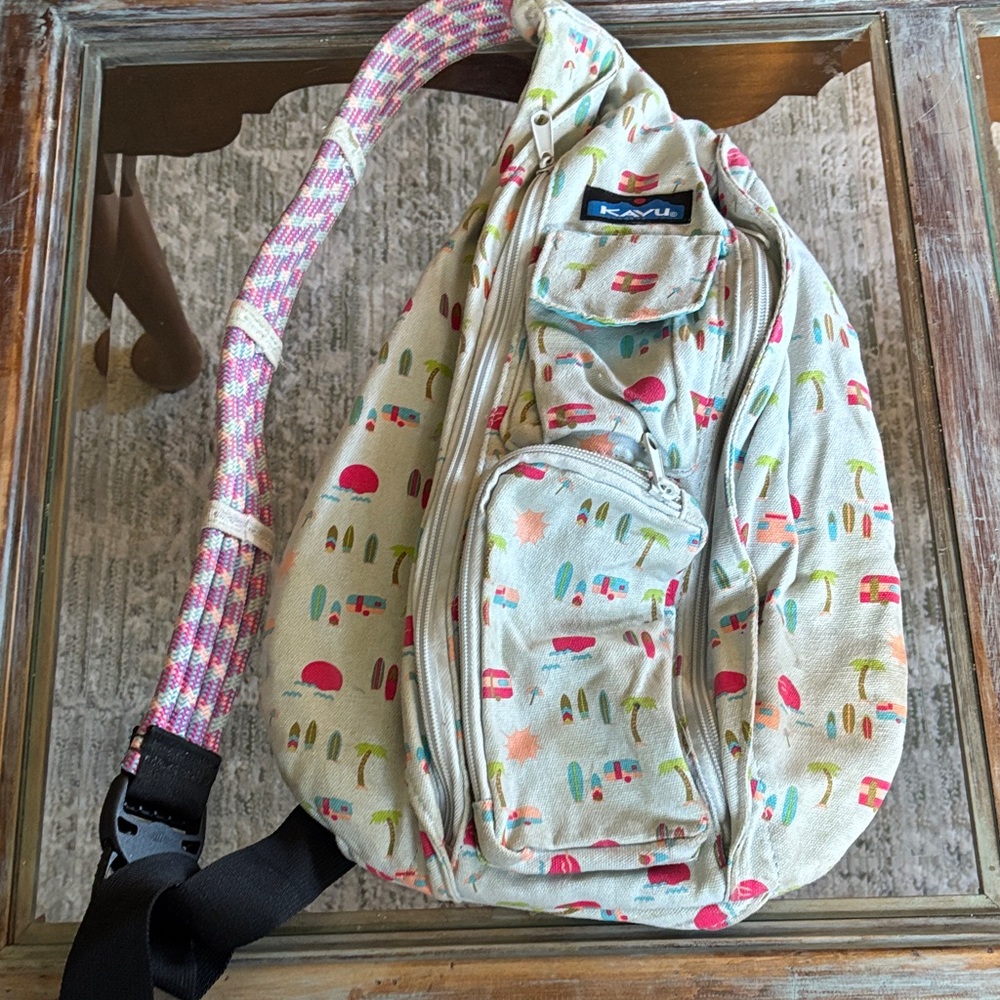 Kavu Cream Sling Backpack with campers and surf boards